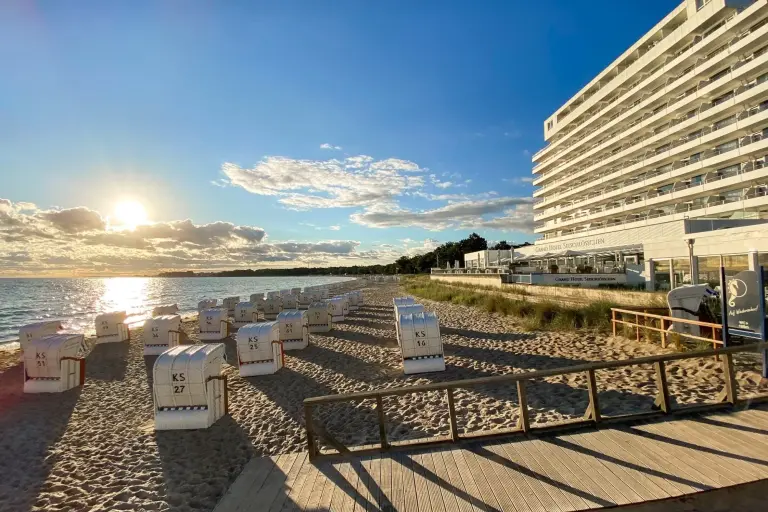 Strandkörbe in der Abendsonne auf dem Strand vor dem Grand Hotel Seeschlösschen am Timmendorfer Strand bei blauem Himmel.