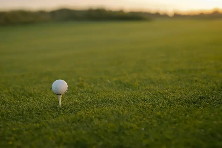 Ein einzelner Golfball steht auf einem Tee im warmen Abendlicht, perfekt für einen entspannten Golfurlaub an der Ostsee.