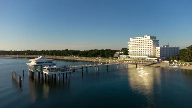 Außenaufnahme des Grand Hotel Seeschlösschen am Timmendorfer Strand mit der Seebrücke in der Abendsonne.